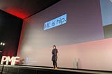 Photo of myself on stage at the conference. Slide text “ML is hip.”