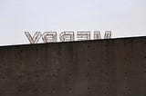 Outdoor Christmas decoration showing the word Merry appearing behind a large and high concrete wall.