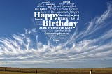 The blue sky, wispy white clouds and the words saying Happy Birthday in numerous languages, the words all formed into a shape of a loveheart.