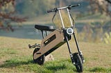 A closer look at the Tom folding electric scooter on a green grassy knoll.