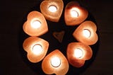 7 heart-shaped salt candles create a circle with the points of each lite candle pointing inward.