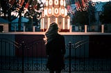 Person stands facing a carnival ride with spinning chairs.