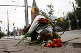 A pile of flowers on the pavement with a building in the background
