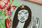 Street art in Sao Paulo of woman with three eyes and holding up a hand with an eye on the palm