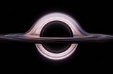 A realistic rendering of a black hole with a glowing event horizon and warped light ring, set against the darkness of space.