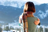 Portrait of a young redhead woman in winter mountains.