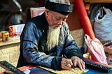 An old man who is writing on a paper.