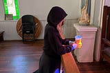 author kneeling in a church holding coffee