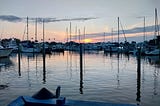 sunset at a small boat marina, from the dock, looking west from Florida’s Gulf Coast the sunset between several small boat masts and across the shimmering smooth surface of the water