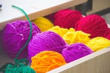 Open drawer with balls of yarn arranged by color.