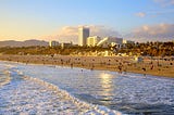 An image of Downtown Santa Monica, CA with the beach in the foreground and several high-rise buildings in the background.
