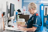 A picture of an NHS nurse at a computer screen in hospital.