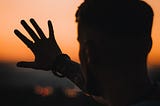man showing one hand at sunset