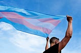 A trans man holding up a Transgender flag