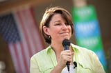 Amy Klobuchar at campaign rally on front lawn of a residence.