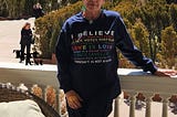 Author standing with shirt on that says: I Believe that no person is illegal