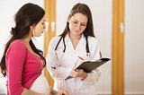 A young woman consults with her doctor, who is listening to her.