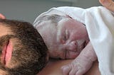 Newborn baby lying on a man’s chest.