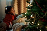 A young girl lying by a Christmas tree, probably in the very early morning!