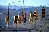 several traffic lights hanging on a wire giving mixed signals