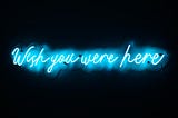 Blue neon sign saying “Wish you were here”