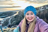 selfie of author in Halden, Norway with a scenic sunset background on a mountain with water below