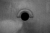 Picture of a round hole in a wooden door. © The author