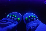 Close-up image of toes with fluorescent green nail polish protruding from beneath baggy trousers
