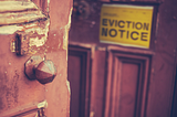 Image description: Broken, old-fashioned door with chipped paint has a yellow sign reading “Eviction Notice” on it. Title: Supreme Court’s decision to block eviction moratorium amid COVID-19 surge will be a public health disaster. Keywords: Supreme Court, eviction moratorium, COVID-19, pandemic, public health, coronavirus