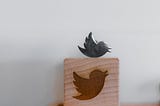 Wood carving of the Twitter logo, with a metallic bird on top