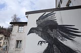 A mural showing a raven with a clockwork in his feathers on a white wall.