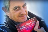 Image of Samarel the erotic artist of ‘Samarel Eros’, holding his sex positions art book ‘Sama Sutra’