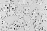 A picture of scattered white puzzle pieces on a white background.