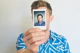 Man holding a photo of himself in front of his face