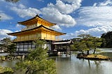 The Golden Pavilion in Kyoto against a blue cloudy sky.