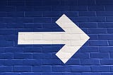 White arrow painted on a blue wall