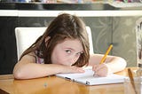 Young girl writing while giving the viewer a side-eye. She looks confident. Creativity. Flow state. Writing.