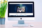 A monitor, keyboard, mouse and pot showing website.