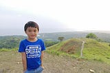 a toddler standing on a hill with overlooking view of the beach and mountains