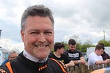 Photo of author in racing suit smiling and looking to camera