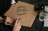 The word “Hello” written in calligraphy on a cardstock.