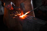 Blacksmith using hammer with forge.