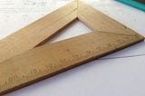 An image of a measuring wooden triangle that depicts the manual art of problem solving