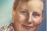 Colourised head and shoulders studio portrait of a young white woman (Elli Immo). The woman is looking into the camera and smiling slightly. Photo has been taken by Kemin Kuvaamo photo studio.