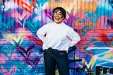 Happy girl with white shirt and blue jeans in front a very colorful wall