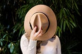 A woman covering her face with a hat