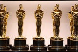 Ten “Oscar” statuettes against a pink background.