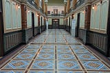 Ornately tiled floor in a long hallway leading to a doorway