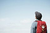 A man with a back pack looking up at the sky.