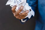 A hand holding a crumpled bunch of papers.